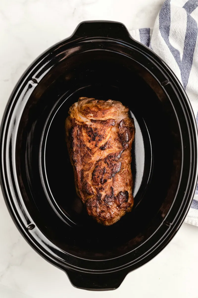 seared pork set in a slow cooker insert