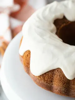 pumpkin bundt cake with cream cheese frosting on white plate