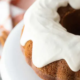 pumpkin bundt cake with cream cheese frosting on white plate