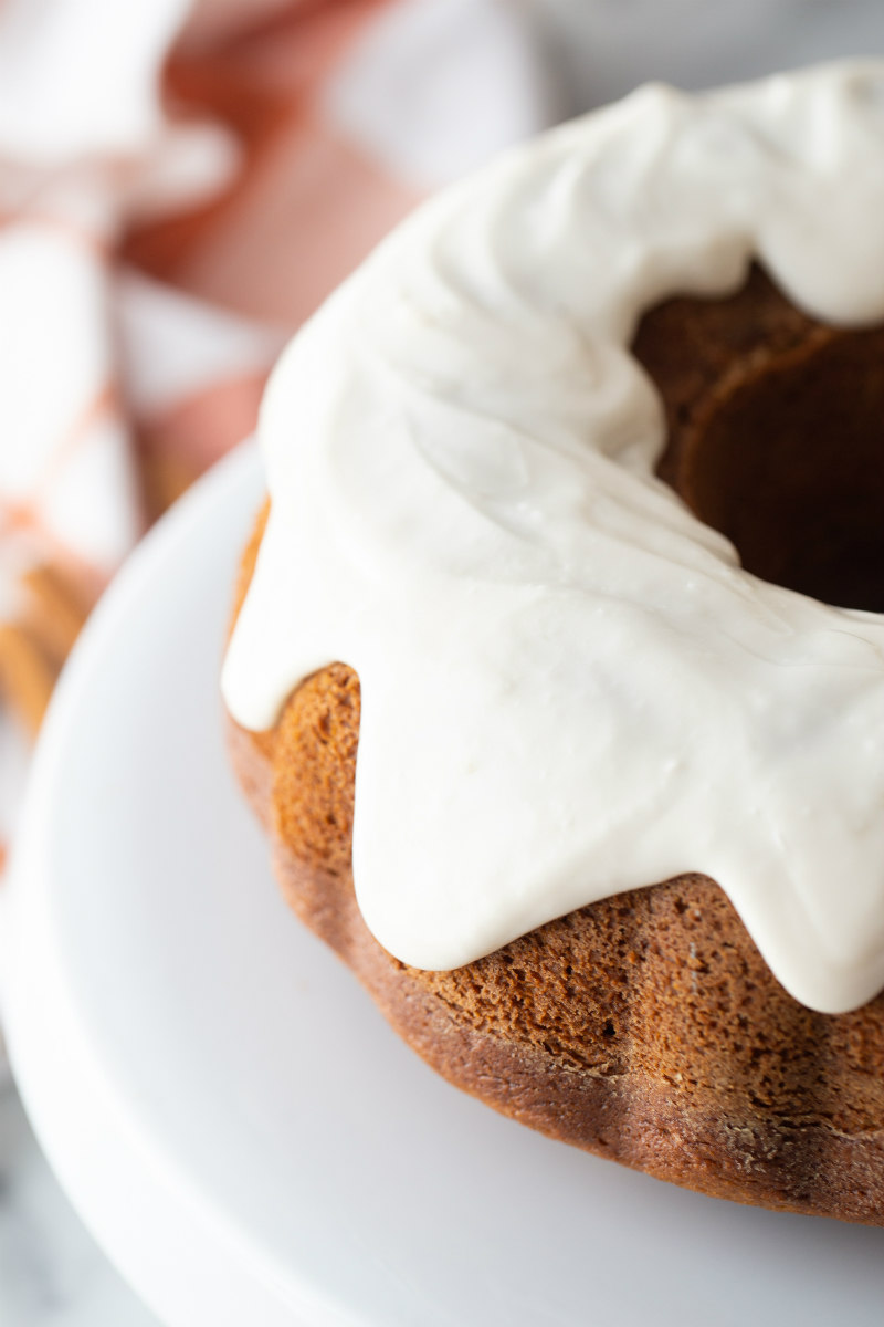 pumpkin bundt cake with cream cheese frosting on white plate