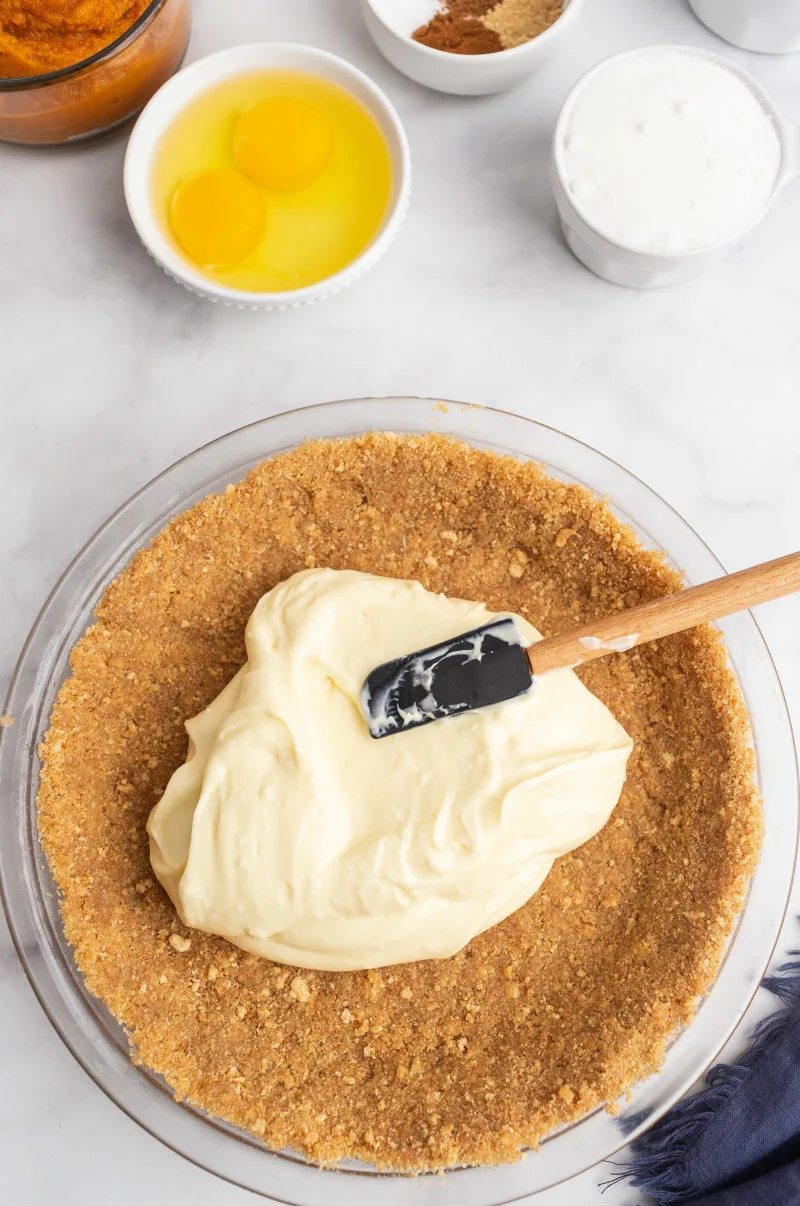 pouring cream cheese layer onto graham cracker crust