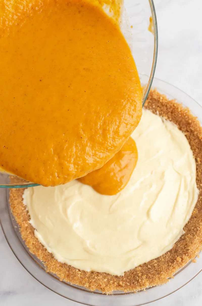 pouring the pumpkin layer onto the cream cheese for pumpkin cream cheese pie