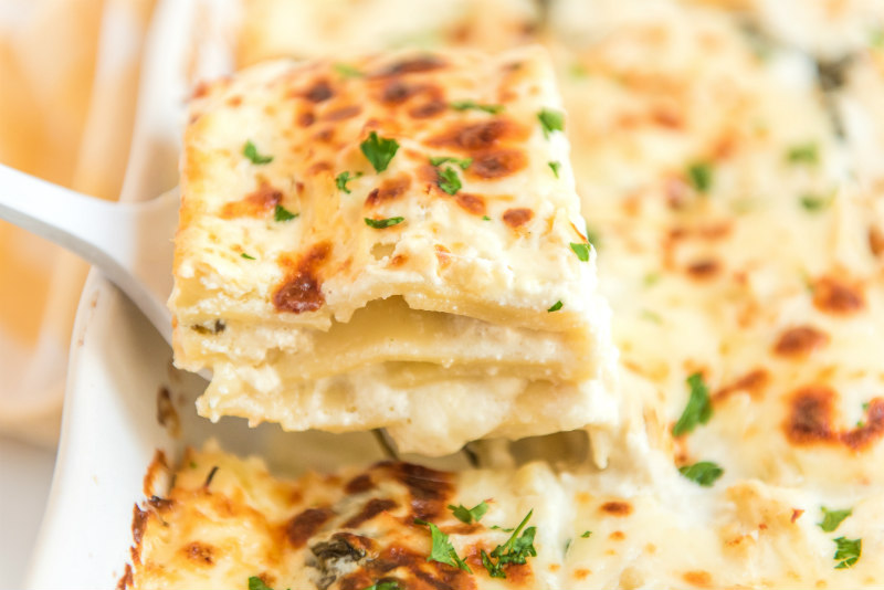 spatula taking slice of white chicken lasagna out of pan