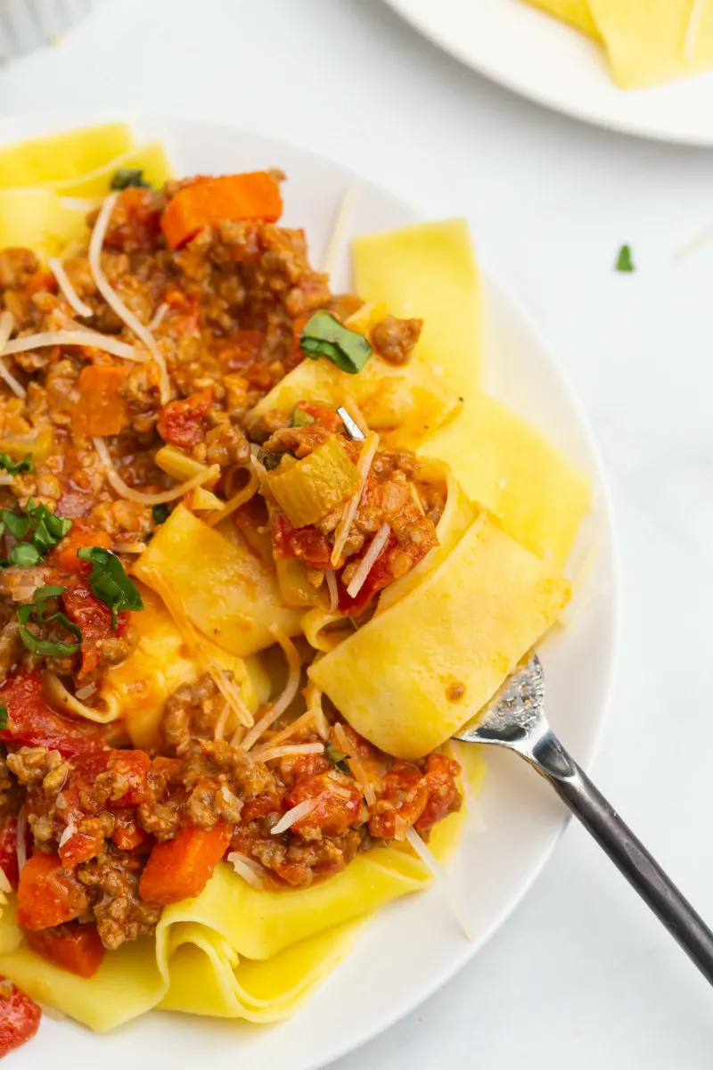 forkful of pappardelle bolognese on a plate