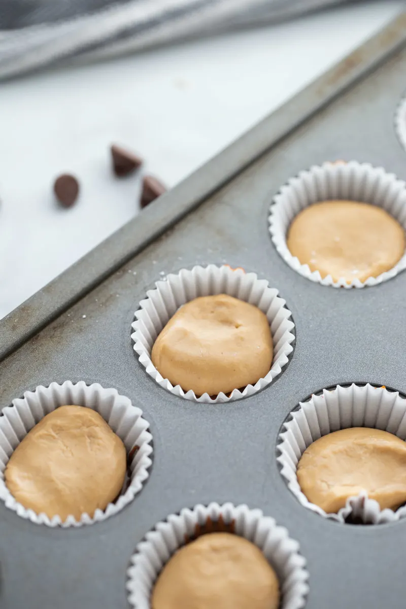 showing process of making peanut butter cups in muffin tin- adding peanut butter