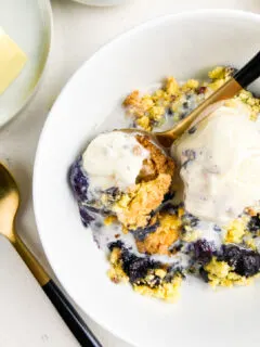 blueberry cobbler in white bowl with ice cream