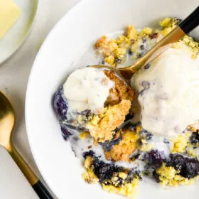 blueberry cobbler in white bowl with ice cream