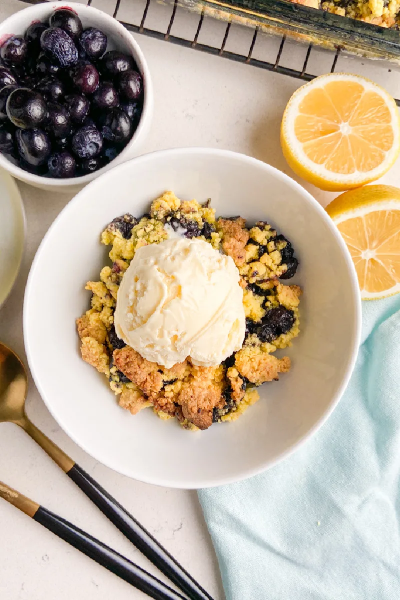 blueberry cobbler in a white bowl with ice cream on top