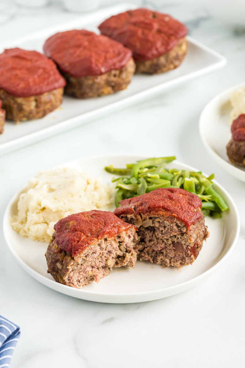 meatloaf cut open on a plate with mashed potatoes and green beans