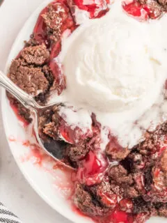 chocolate cherry dump cake with ice cream and spoon on white plate