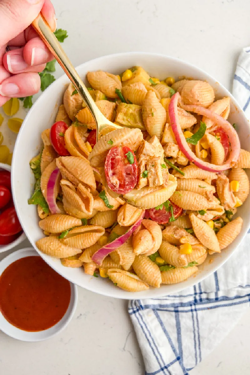 Hand taking spoonful of BBQ Chicken Pasta Salad out of bowl