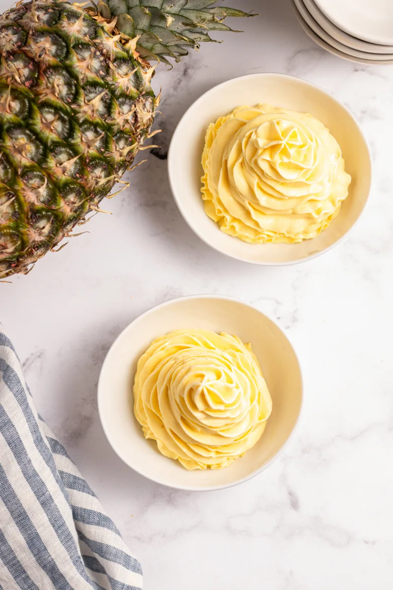 two bowls of dole whip with pineapple in background