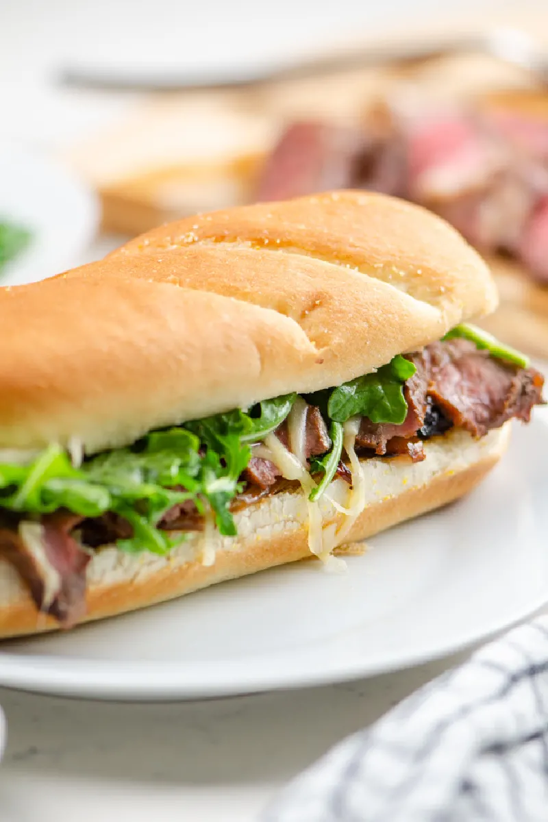 steak sandwich on long roll on white plate