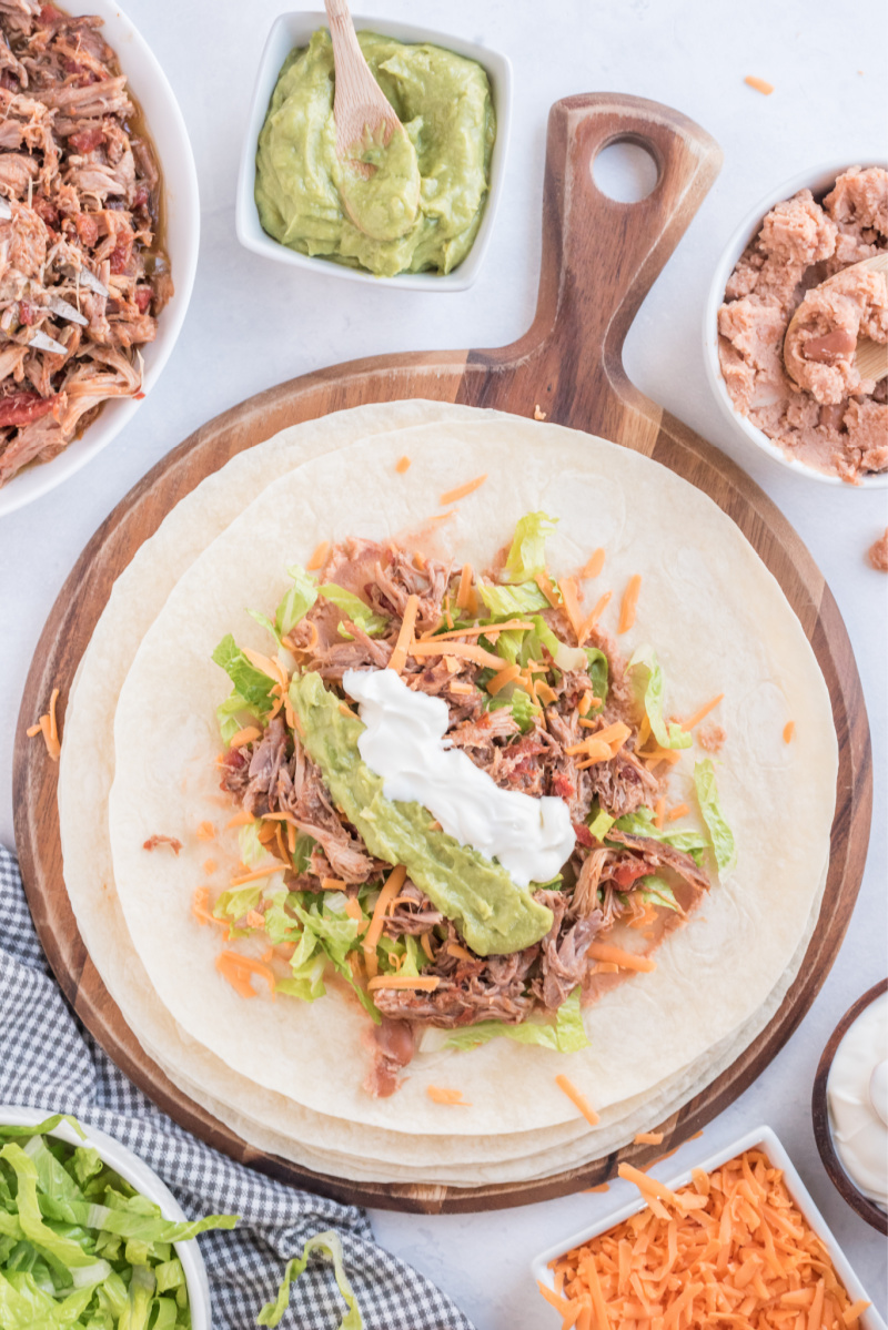 showing assembly of making a burrito with filling in a flour tortilla