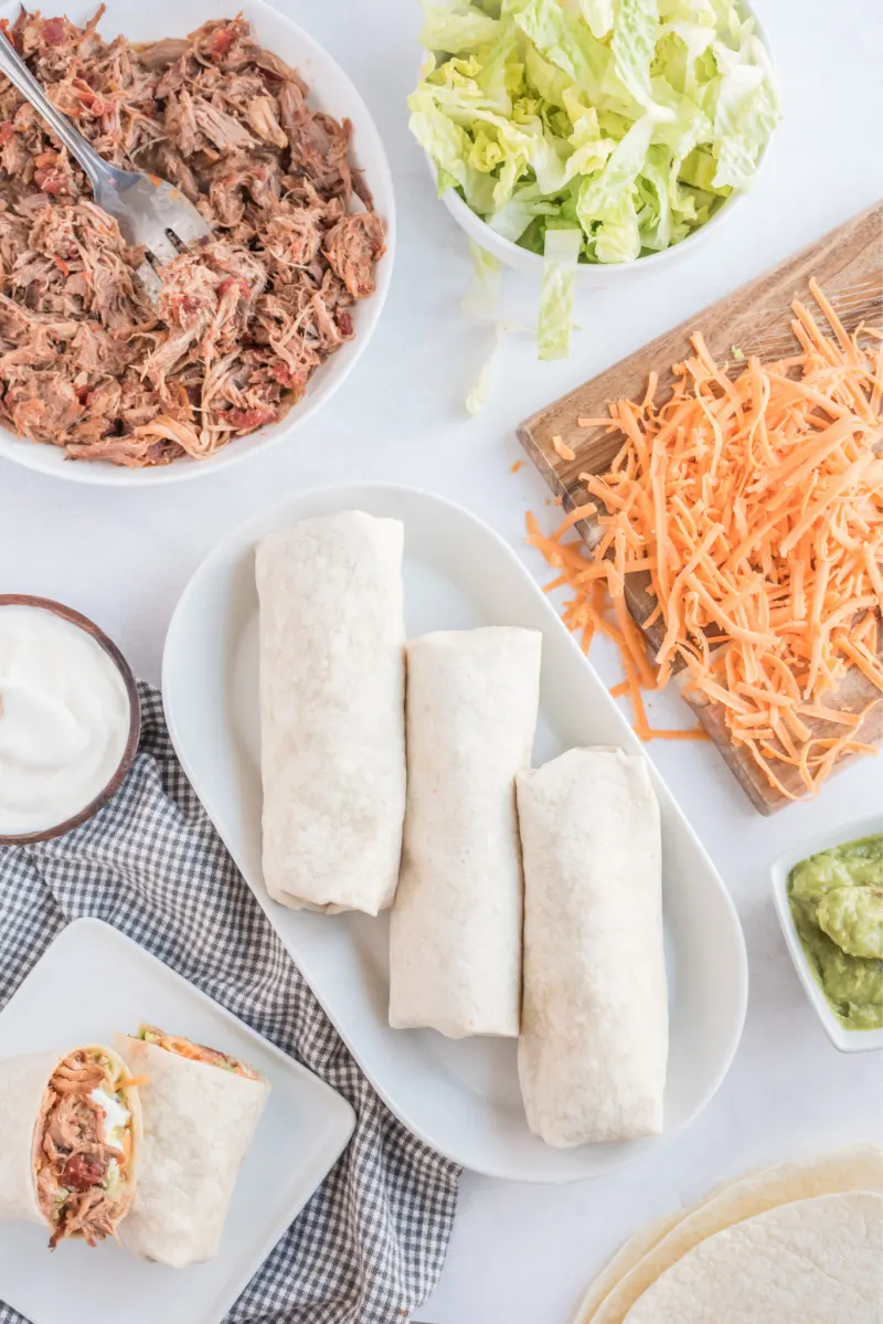 burritos wrapped up and surrounded by fixings