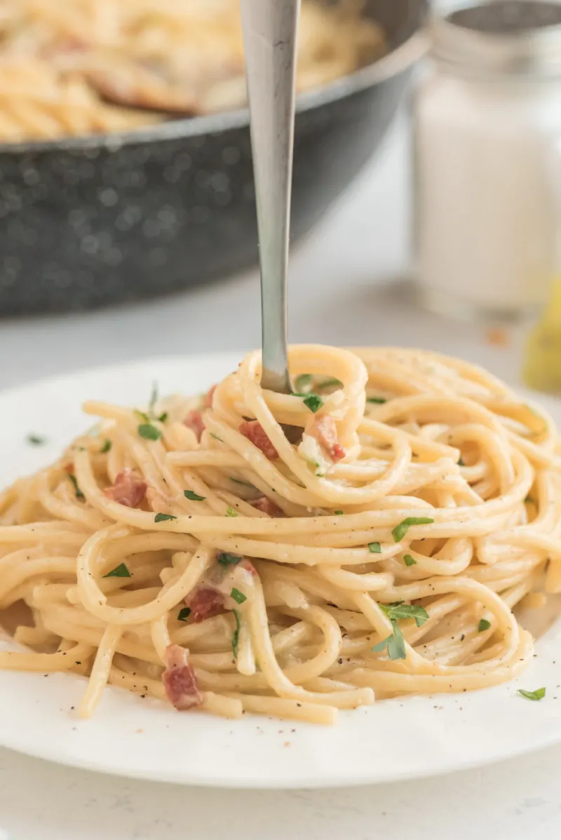 carbonara on a white plate with a fork