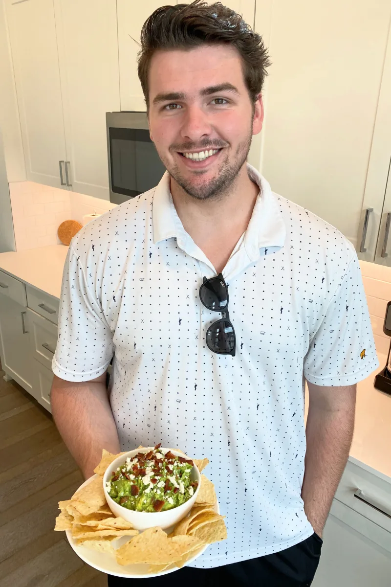 recipeboy holding bacon and cotija cheese guacamole with chips