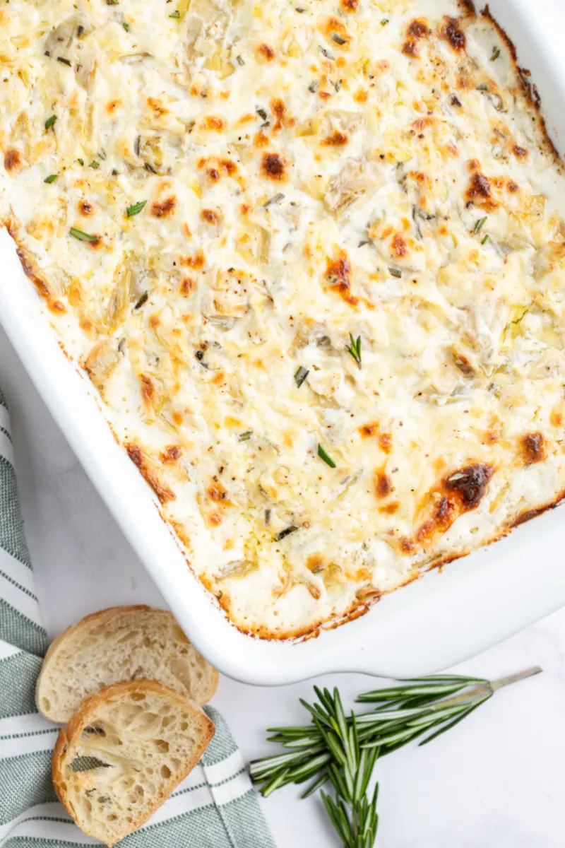 cheesy lemon rosemary artichoke dip in a white dish