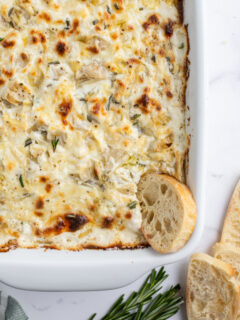 cheesy lemon rosemary artichoke dip in casserole dish