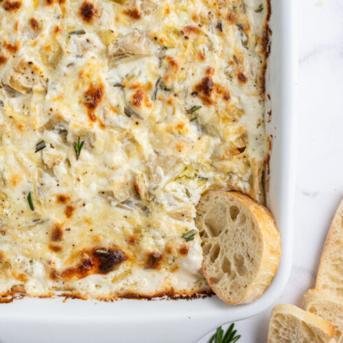 cheesy lemon rosemary artichoke dip in casserole dish