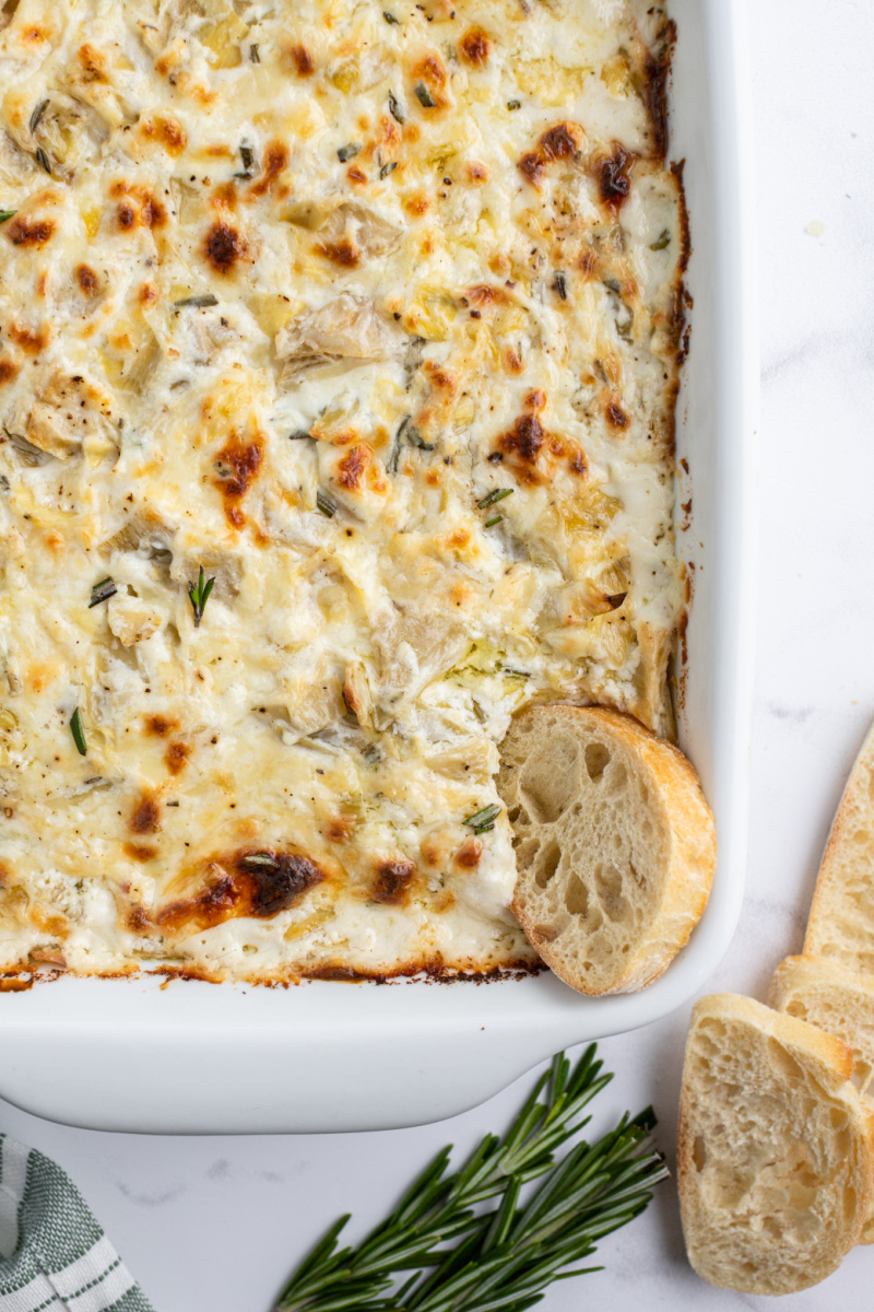 cheesy lemon rosemary artichoke dip in casserole dish