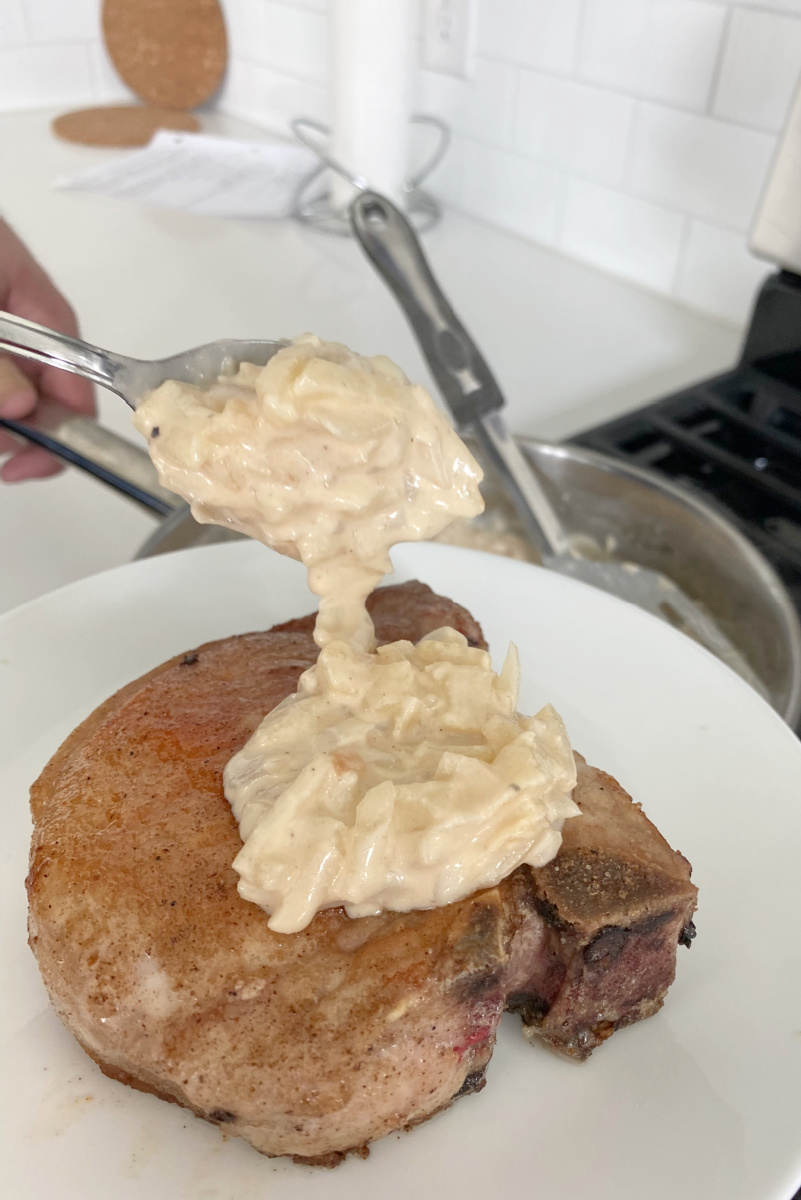 spooning apple sauce onto pork chop