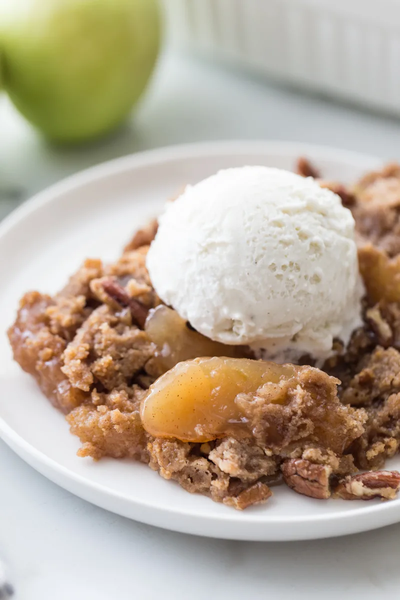 serving of caramel apple dump cake on plate with ice cream