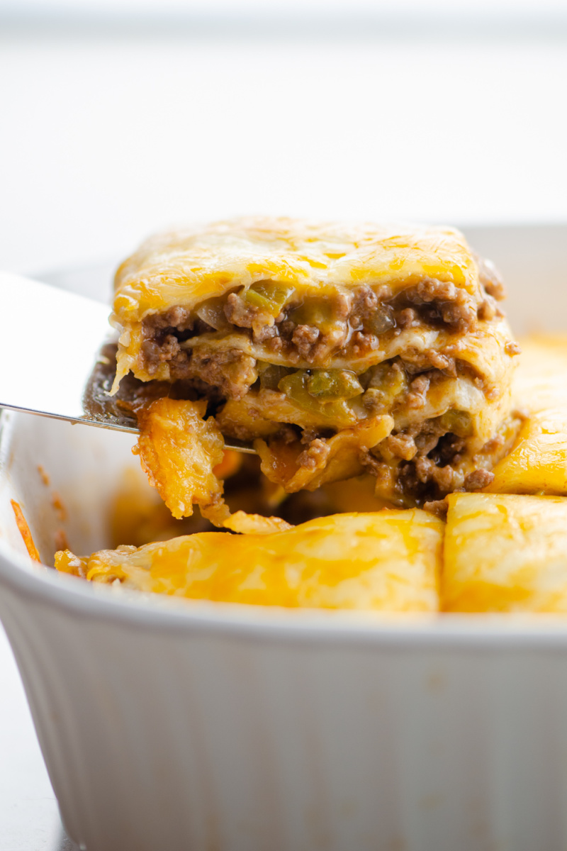 spatula taking out piece of tortilla casserole out of dish