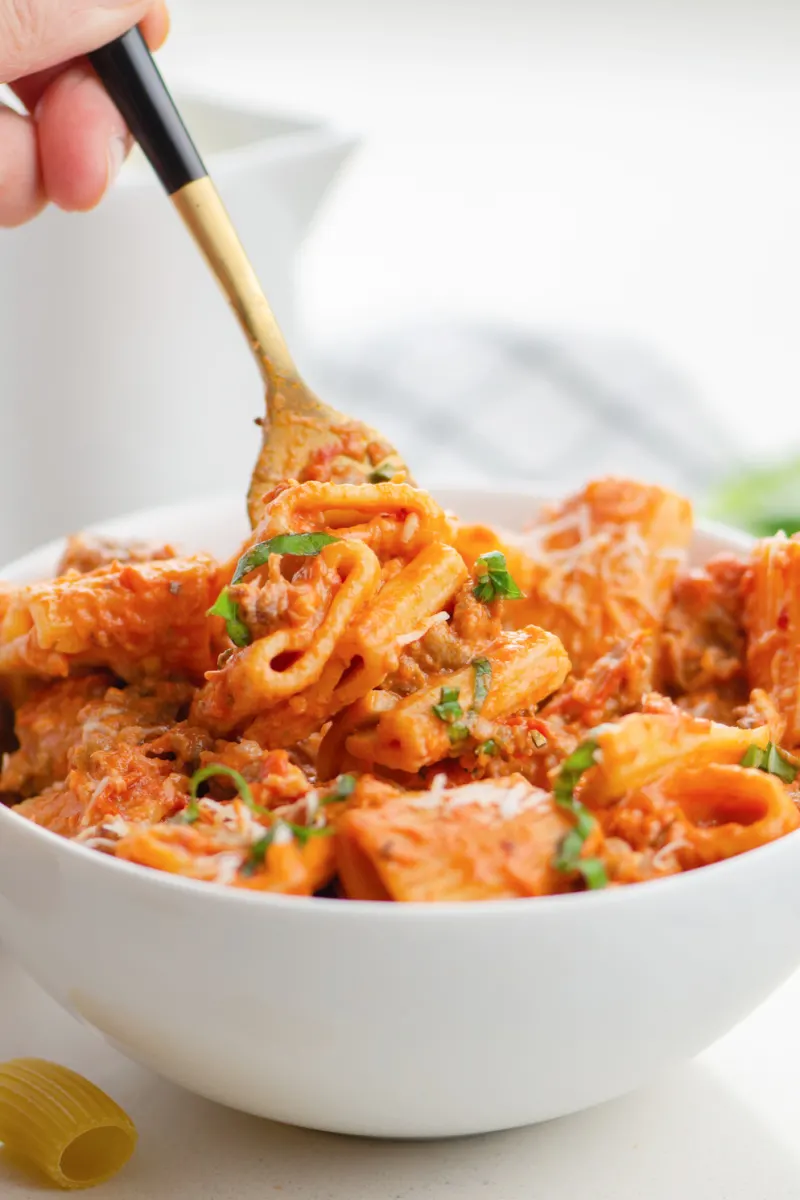 fork taking tomato rigatoni out of bowl