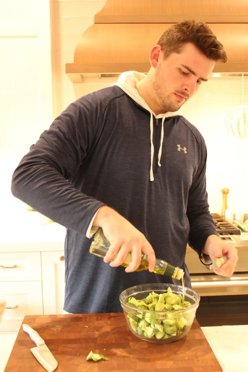 recipeboy pouring oil onto brussels sprouts in bowl