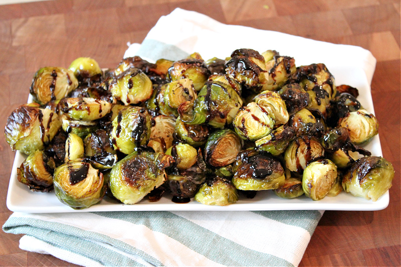 roasted brussels sprouts on a platter with balsamic glaze