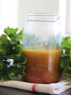 jar of salad dressing surrounded by lettuce