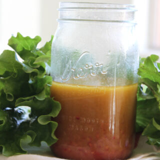 jar of salad dressing surrounded by lettuce