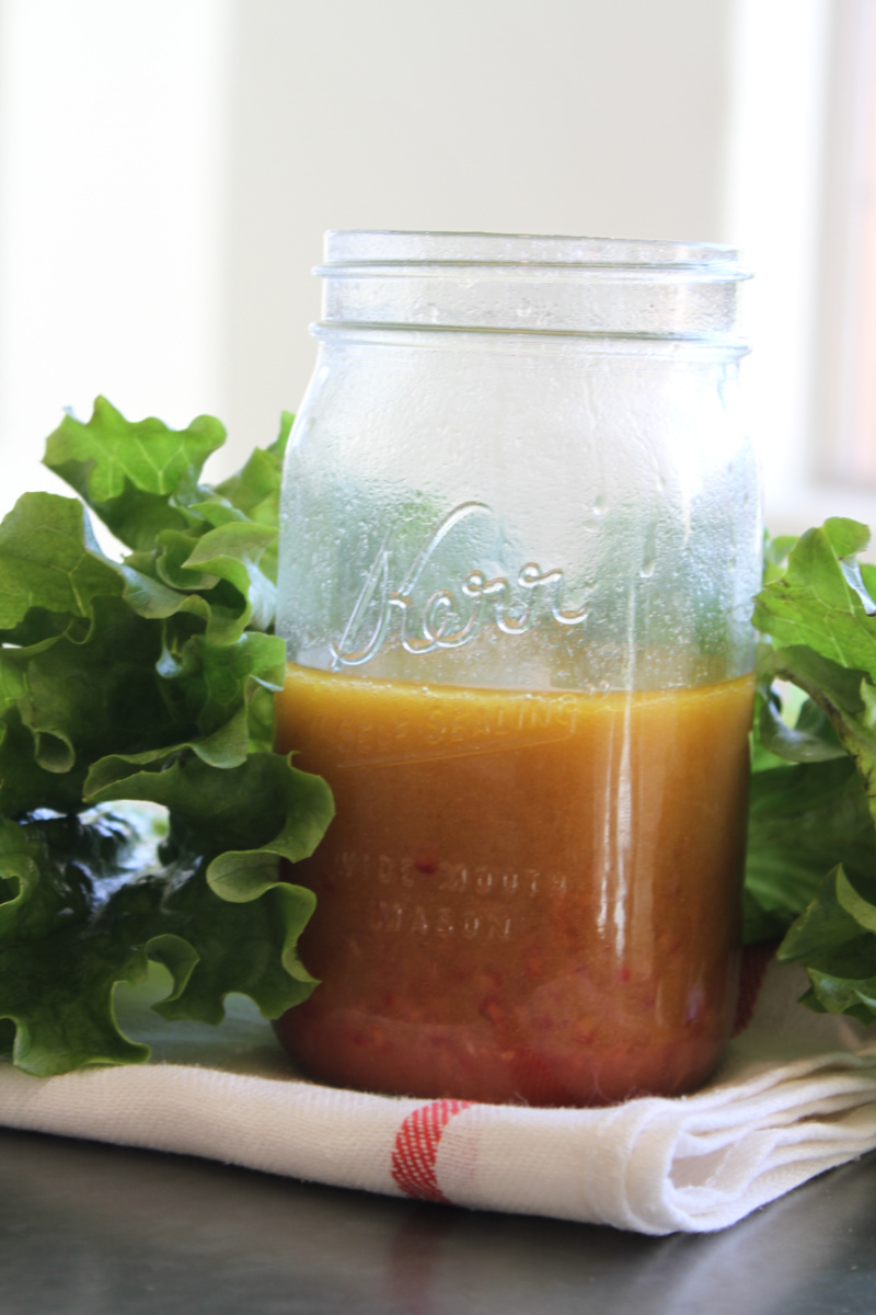 jar of salad dressing surrounded by lettuce