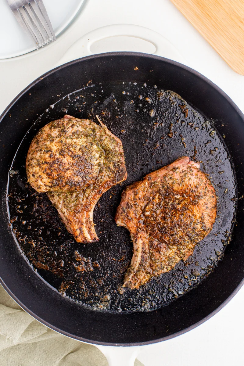 two porks chops cooked in a black skillet