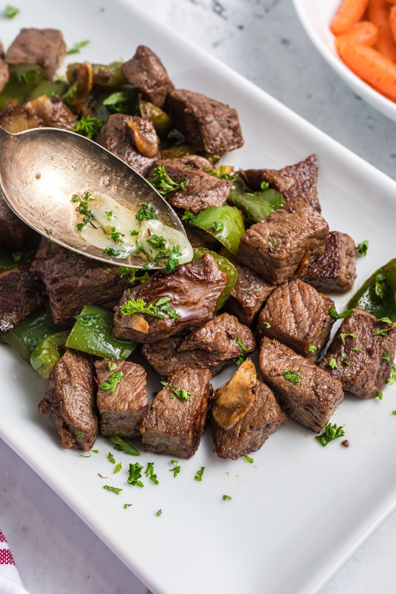 spooning butter sauce onto steak bites