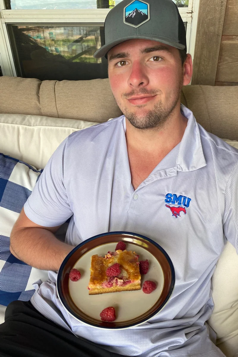 recipeboy holding a slice of raspberry gooey butter cake on a plate