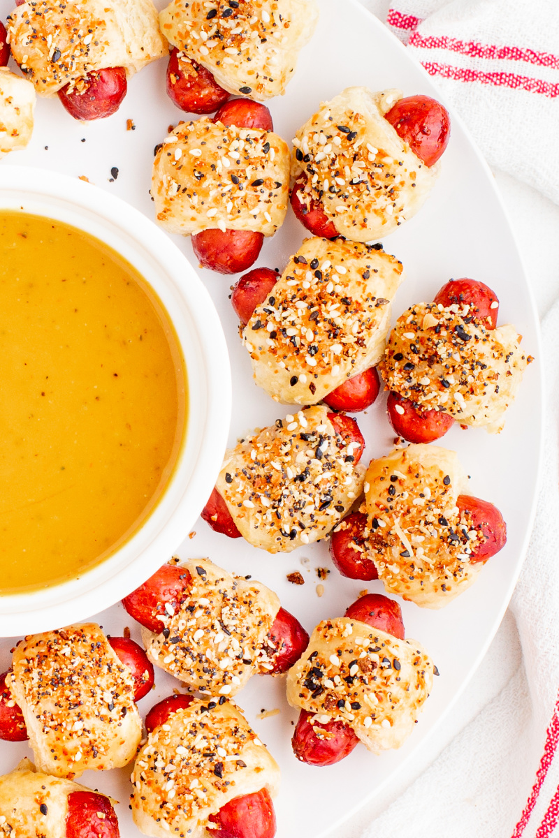 pigs in a blanket on a plate with a bowl of mustard dipping sauce