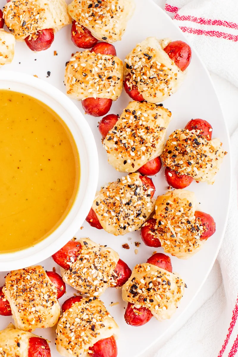 pigs in a blanket on a plate with a bowl of mustard dipping sauce