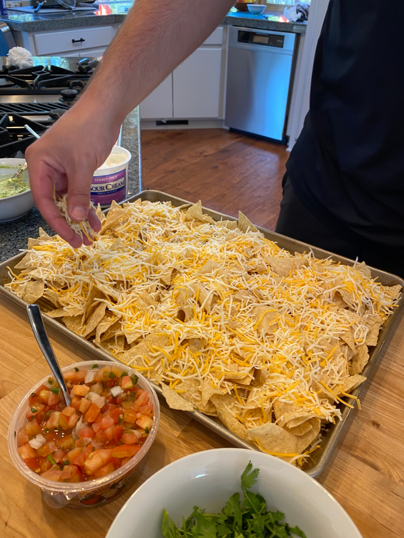 sprinkling cheese on tortilla chips for nachos