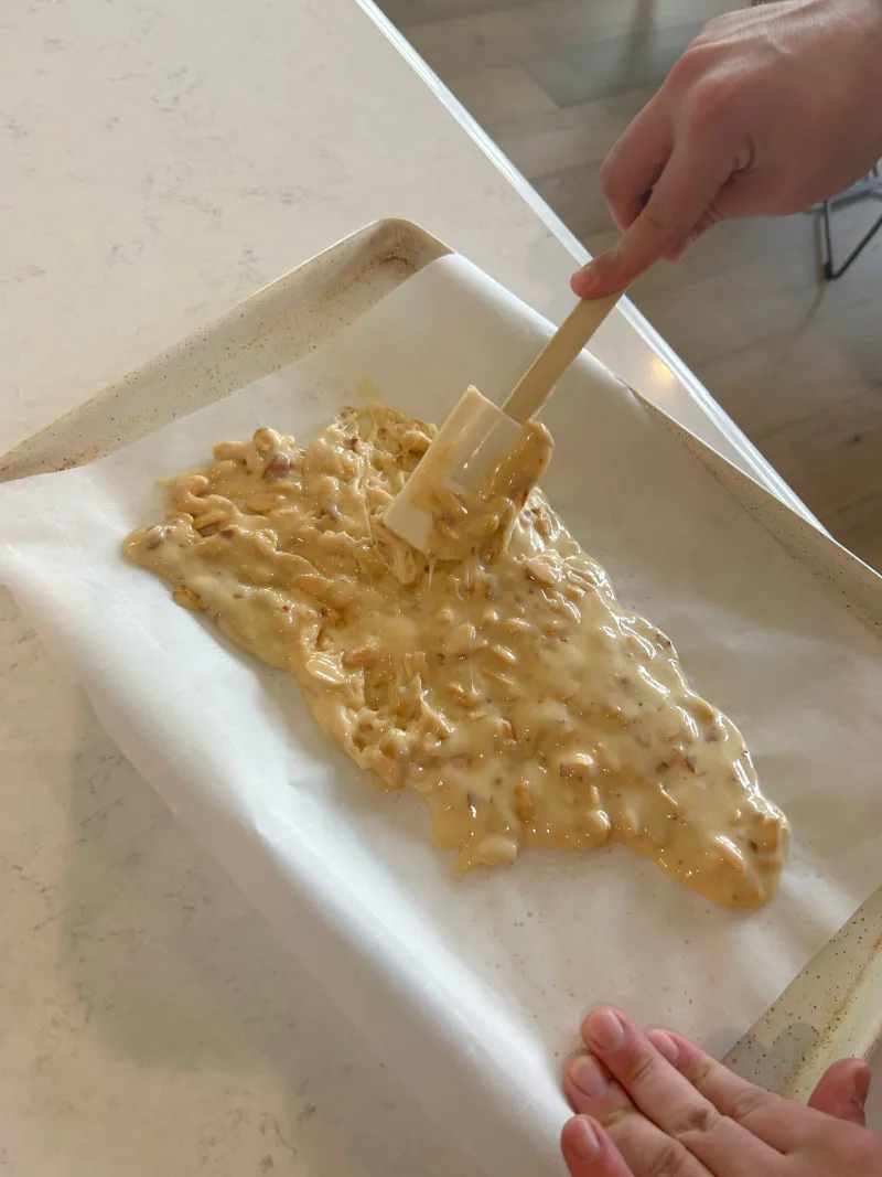 spreading peanut brittle onto a baking sheet