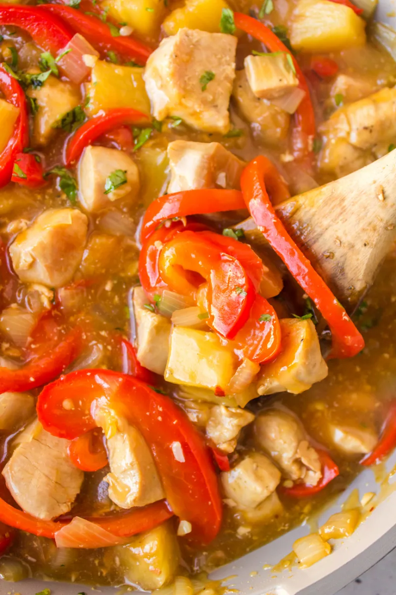 spooning in skillet of pineapple chicken ginger stir fry