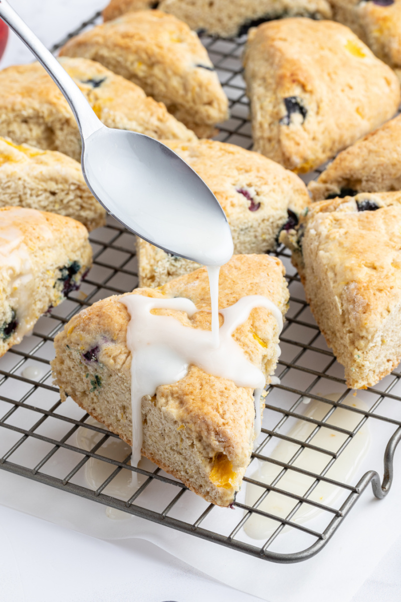 drizzling icing onto blueberry peach scones