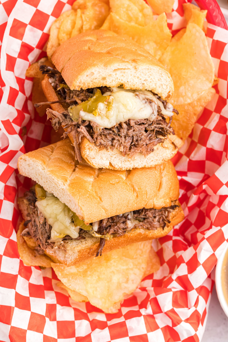 two halves of crockpot italian beef sandwiches in a red and white checked basket