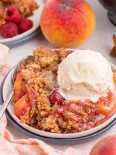 raspberry peach crumble in a dish with vanilla ice cream on top