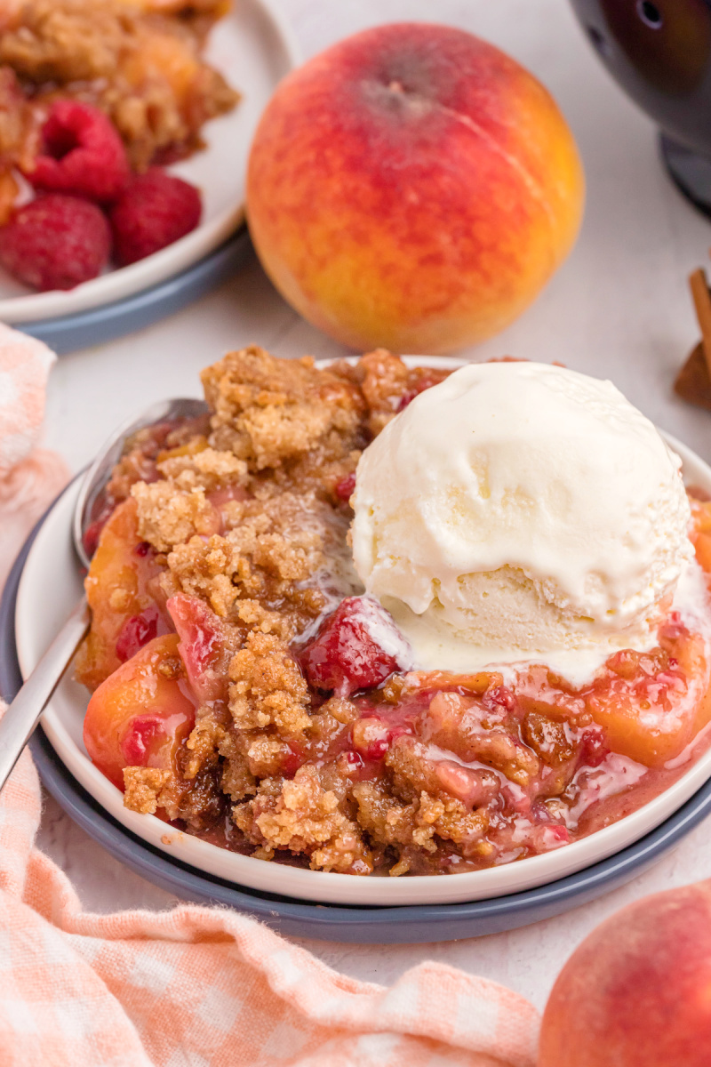 raspberry peach crumble in a dish with vanilla ice cream on top