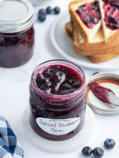 open jar of blueberry jam with toast in background