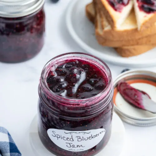 open jar of blueberry jam with toast in background