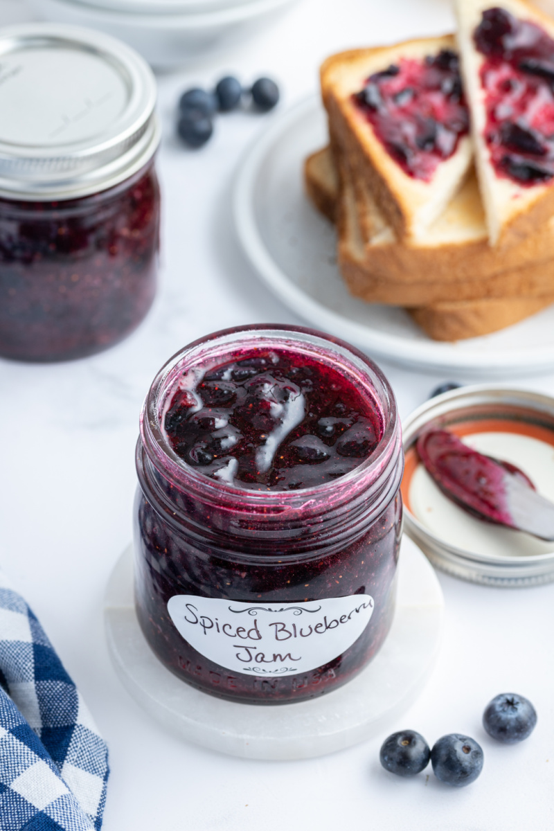 open jar of blueberry jam with toast in background