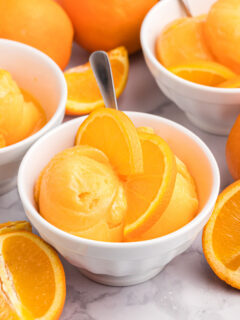 orange sherbet in bowl with orange slices